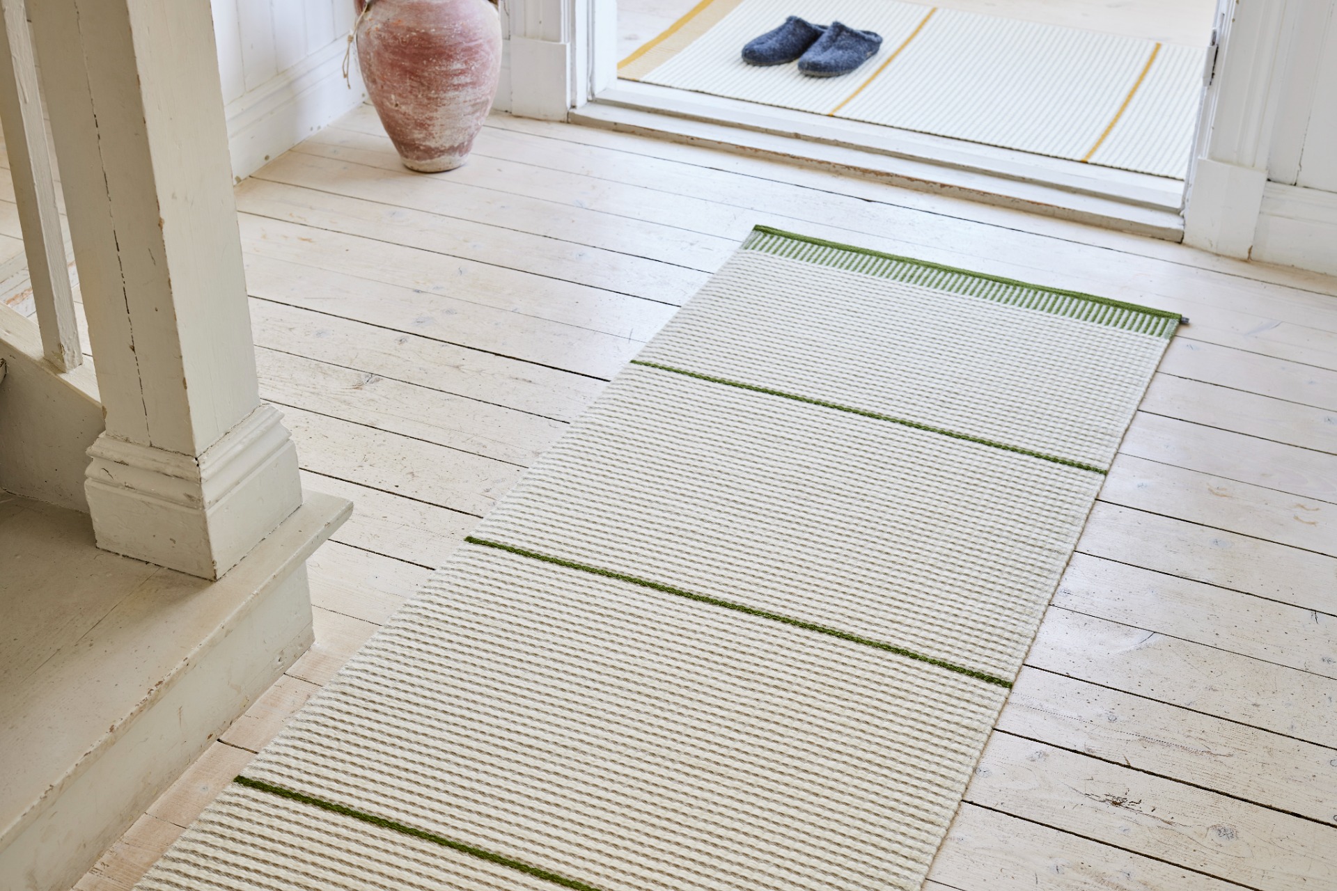 En grønstribet plastikmåtte, der ligger i entréen